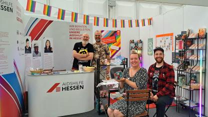 Infostand der Aidshilfen bei der Ausstellung "Treffpunkt Hessen". Vier Mitarbeitende der Aidshilfe Gießen.
