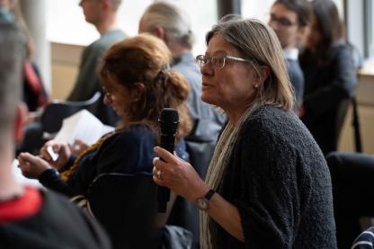 Eine Person im Publikum beteiligt sich an der Diskussion.